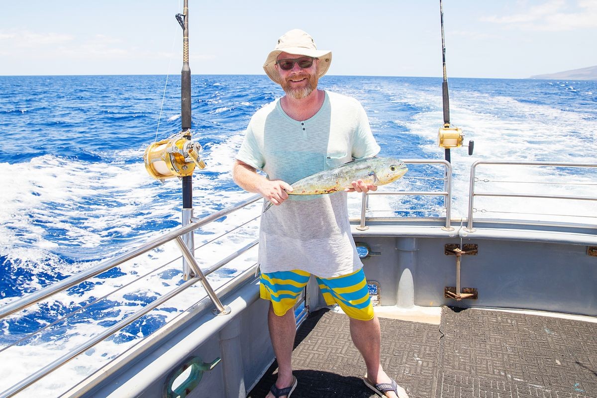 Man holding fresh caught Mahi Mahi on ocean boat